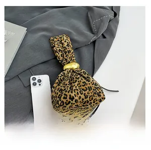 Detailed macro view of leopard print canvas bag with golden oval ring and smartphone for scale