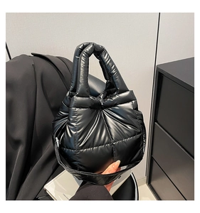 Detailed view of black puffer shoulder bag with padded quilted texture and glossy finish