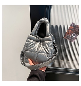Detail of silver quilted down tote bag with metallic finish and padded top handle