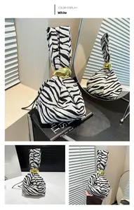 Detail of zebra print fabric handbag featuring a sleek gold metallic handle hardware