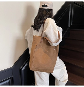 Detail view of a large vintage brown canvas tote bag carried by a model on stairs