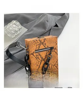 Detail of brown python skin texture crossbody bag with black plastic chain and lock