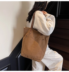 Detail of vintage brown canvas tote bag featuring leather shoulder straps and side metal rivets