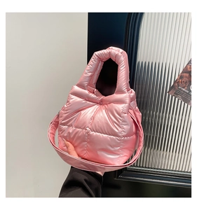 Detail of light pink quilted puffer bag with glossy satin finish and padded handles
