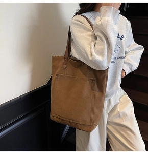 Detailed view of large front pocket on retro brown canvas tote bag with long straps