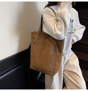 Detail view of large brown canvas tote bag with front pocket and shoulder straps