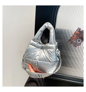Detailed close-up of quilted silver metallic puffer bag with soft padded handles