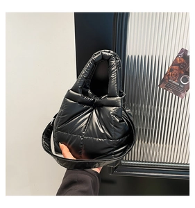 Detail of black quilted down-filled tote bag with glossy nylon finish and soft handle