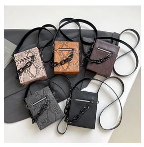 Flat lay of multiple faux snakeskin crossbody bags in five colors with chunky chain detail