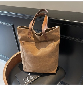 Detailed view of durable brown canvas tote bag with leather handles and metal rivets