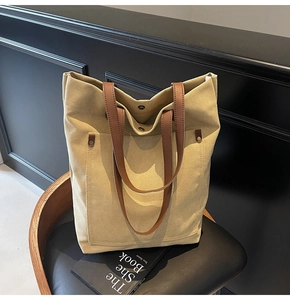 Detailed view of canvas tote bag with brown leather straps and metal snap button