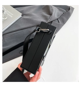 Detail view of black hard shell box bag showing matte texture and silver metal lock