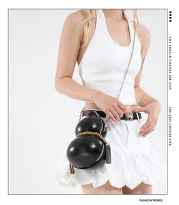 Detailed view of the black gourd-shaped shoulder bag with woven cord and chain strap