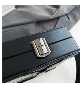 Detail of black leather box with a polished silver metal buckle and lychee texture