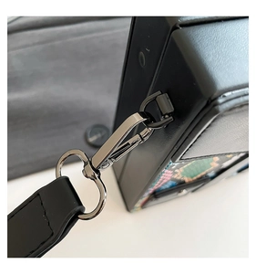 Macro shot of durable gunmetal lobster clasp and textured black leather bag strap detail