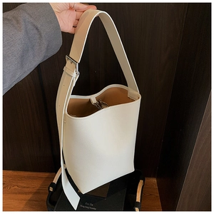Detail der cremeweißen Leder-Eimertasche mit breitem Gurt und silberner Metallschnalle