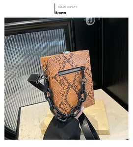 Detail of brown snake skin texture and bold black chain handle on fashion crossbody bag