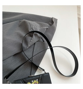 Detail view of mini crossbody bag with black triangle panels and snakeskin texture accent