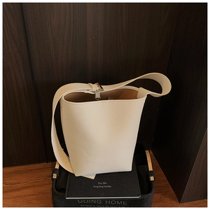 Detail der weißen Eimer-Tasche mit Lychee-Lederstruktur und goldener Metallschnalle