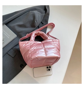 Detail view of pink quilted down tote bag with metallic finish on dark grey blazer