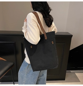 Detail showing vintage black canvas tote bag with brown leather straps on model shoulder