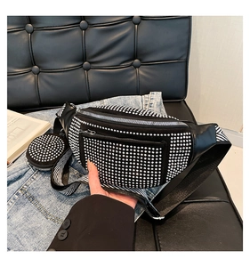 Close-up of black leather chest bag with rhinestones and striped wide shoulder strap