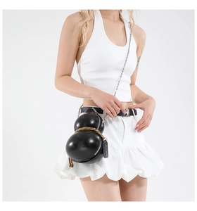 Detail of black gourd-shaped crossbody bag with decorative rope and silver metal chain