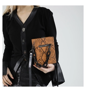 Detail of the vintage box bag featuring brown snake pattern texture and chunky black chain