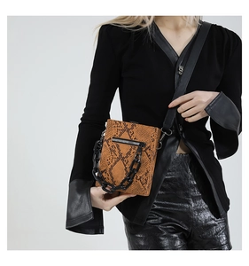 Macro detail of brown snakeskin texture crossbody bag with bold resin chain strap