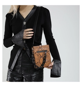 Detail of a brown snakeskin mini square bag with black chunky chain and metallic zipper