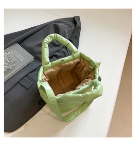 Macro shot of light green quilted tote bag interior with magnetic closure and inner lining