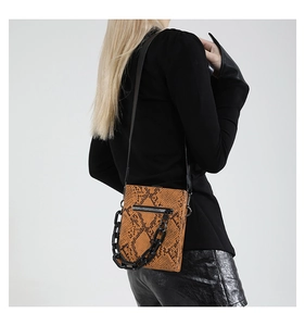 Detail of orange snakeskin textured crossbody bag with black resin chain and zipper
