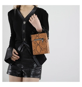 Detail of snake pattern texture on box handbag with chunky black acrylic chain handle
