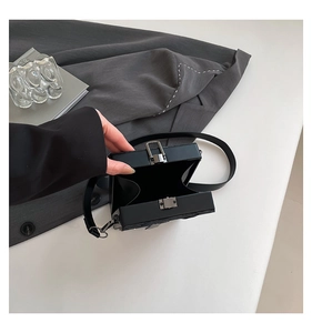 Detail of black hard shell crossbody box bag showing interior storage and metal lock