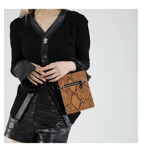 Detailed macro view of the brown snakeskin pattern and bold black chain strap on crossbody bag