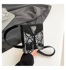 Detail of creative suit-style hardshell crossbody bag with snake print and metal rivets