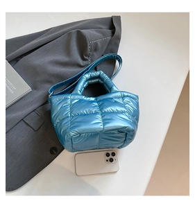 Detail of blue quilted down tote bag with metallic finish and top handle straps