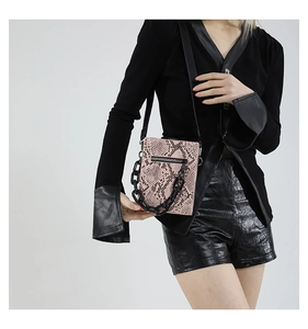 Detail of pink snakeskin pattern small crossbody bag with chunky black acrylic chain