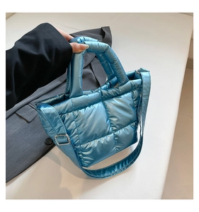 Detail view of light blue puffer bag with quilted glossy fabric and silver buckle
