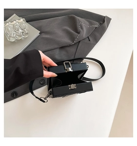 Detail view of a black hard-shell box bag featuring a silver metal press lock and strap