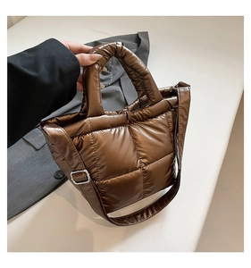 Macro shot of chocolate brown quilted down bag with metallic sheen and strap detail