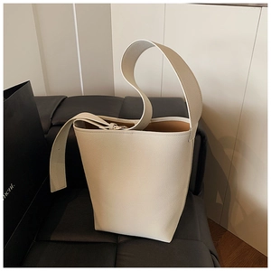 Detailansicht der cremefarbenen Eimertasche aus strukturiertem Leder mit breitem Gurt