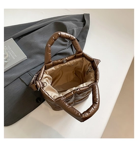 Detail of coffee quilted puffer tote bag with magnetic clasp and satin finish