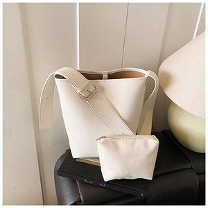 Nahaufnahme der weißen Eimertasche mit Kieselmaserung, breitem Riemen und kleiner Tasche