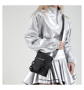 Detailed view of black litchi pattern leather crossbody bag with chunky chain on model