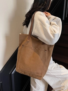 Vintage brown canvas tote bag with front pocket and leather handles worn by a model