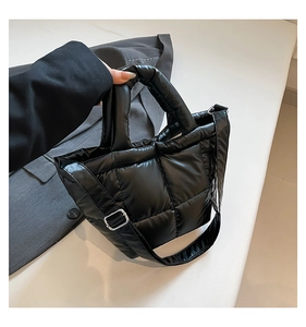 Close-up of black quilted down tote bag with silver metal buckles and refined nylon texture