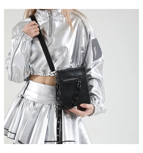 Detail of black textured crossbody bag with thick resin chain on metallic outfit