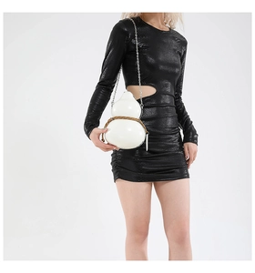 Detail of white gourd-shaped crossbody bag with silver chain and brown cord on model