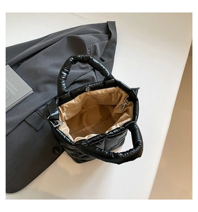 Detailed top view of black quilted puffer bag showing khaki lining and silver snap closure